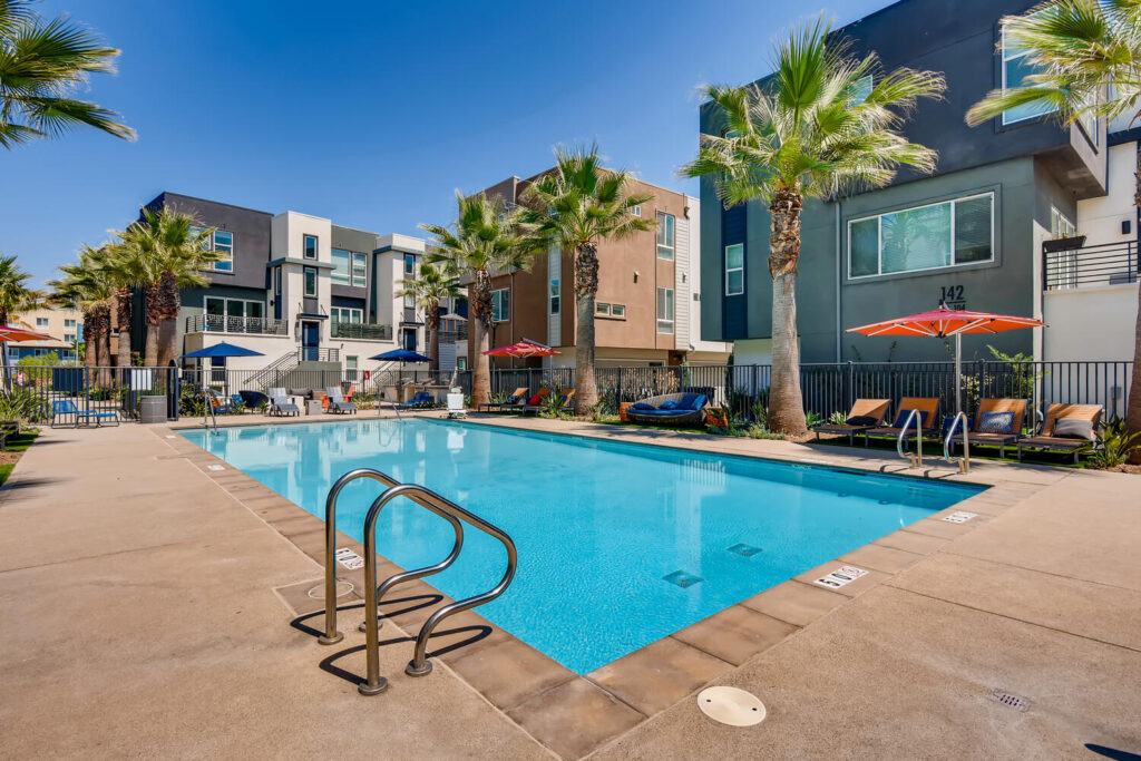Pool with deck chairs, umbrellas, and palm trees