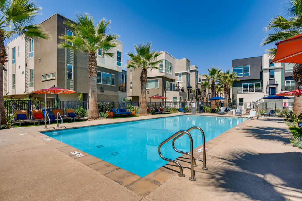 Pool with deck chairs, umbrellas, and palm trees