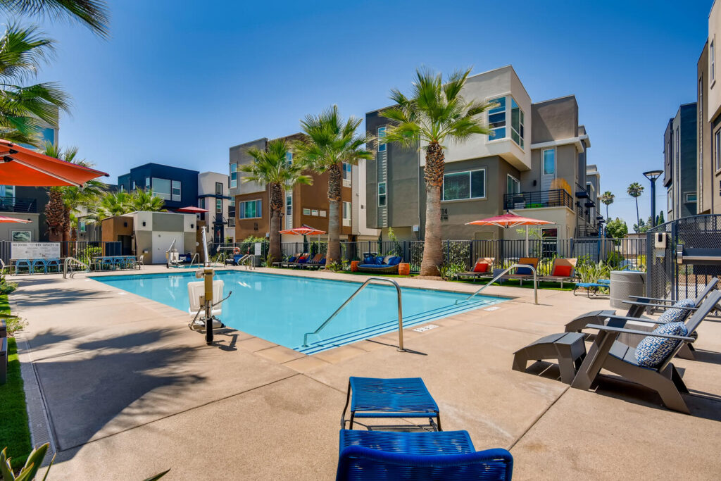 Pool with deck chairs, umbrellas, and palm trees