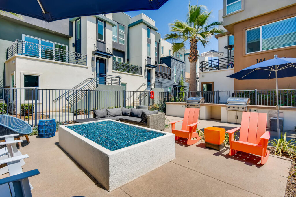 Sitting area by the pool with chairs around a fire pit and grills