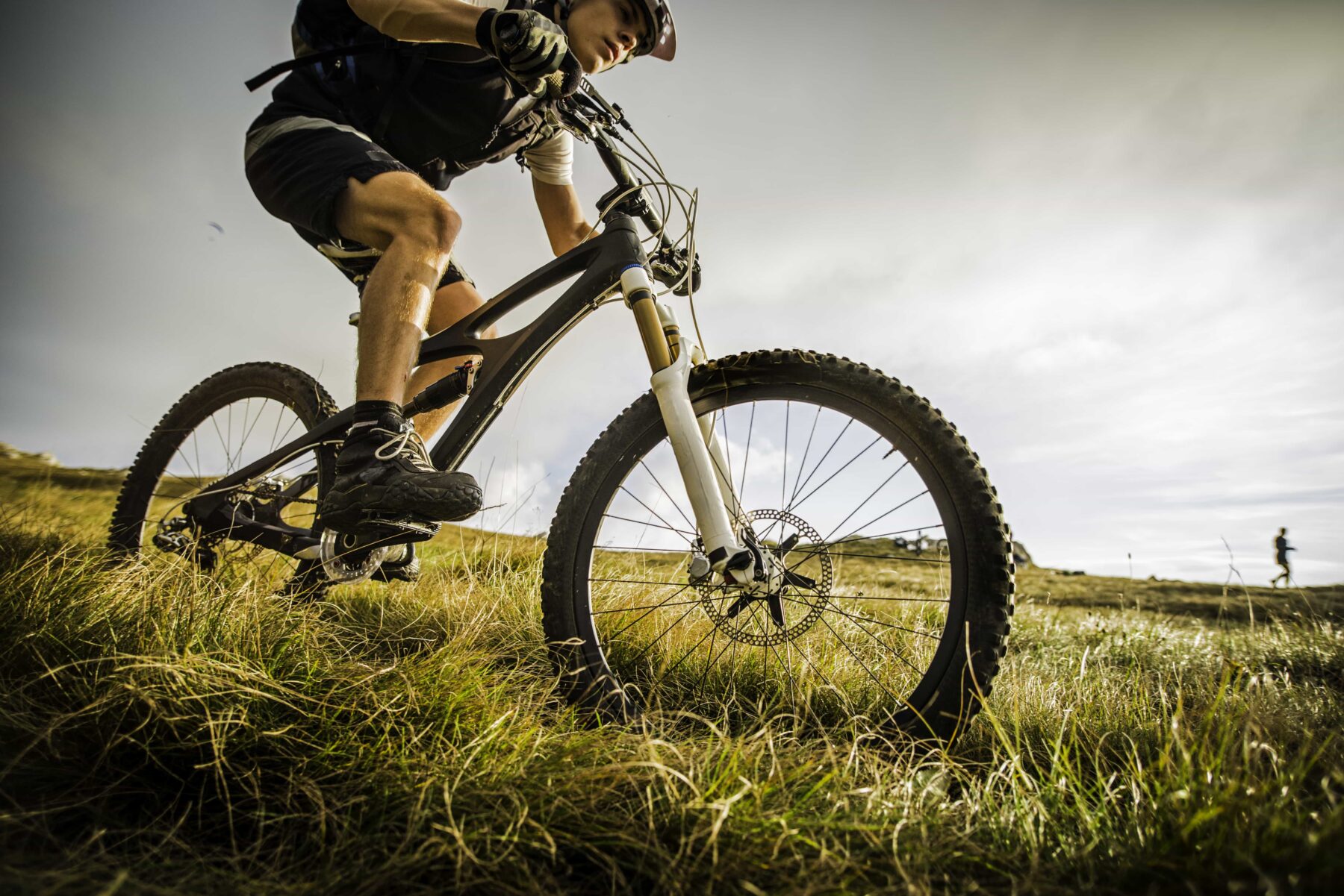 man riding a bike down a grassy hill