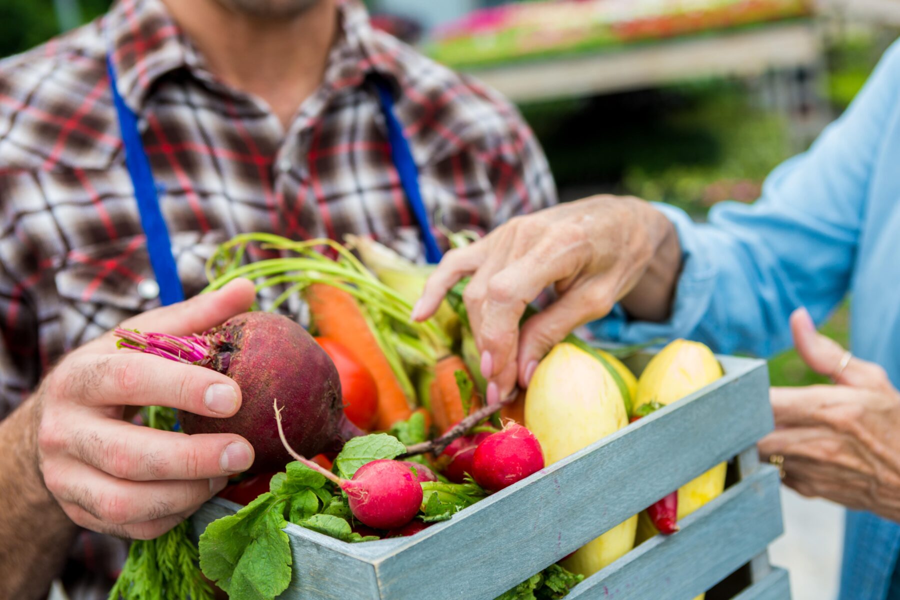 Man holding blue basket of veggies